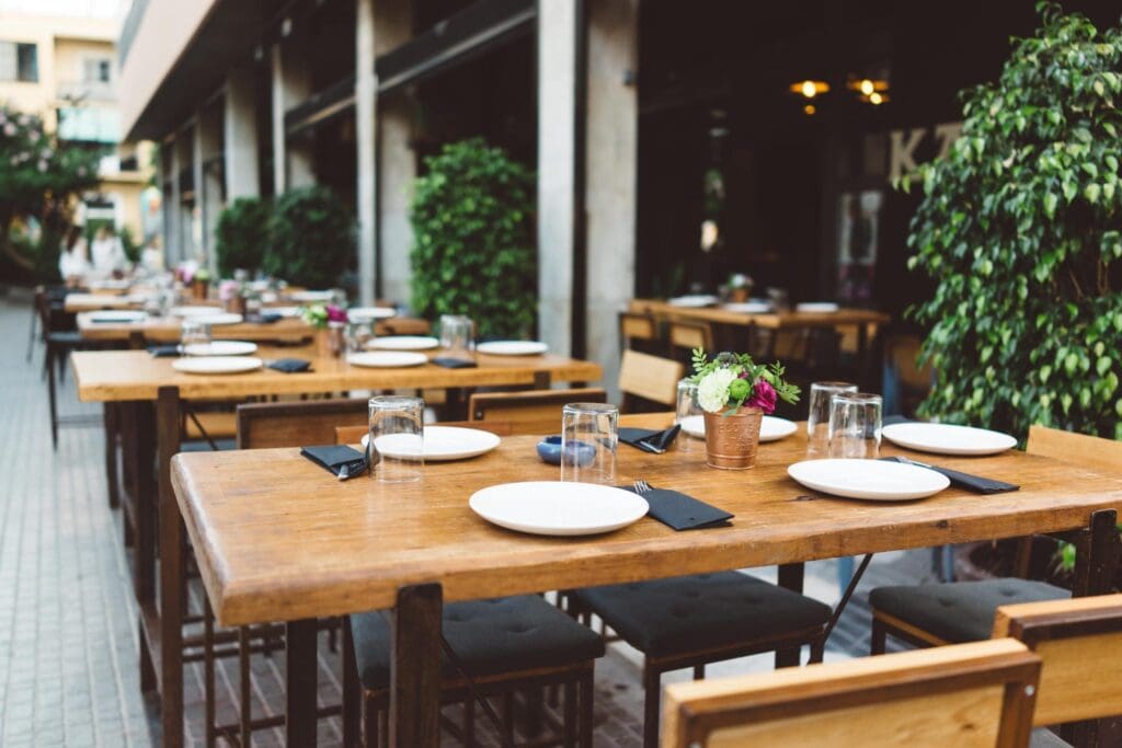 Server handing a dish across the table at an outdoor restaurant patio enclosed with Phantom Screens.