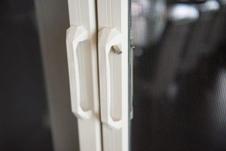 Close-up view of Phantom Screens handles seamlessly meeting at the center of exterior French doors.